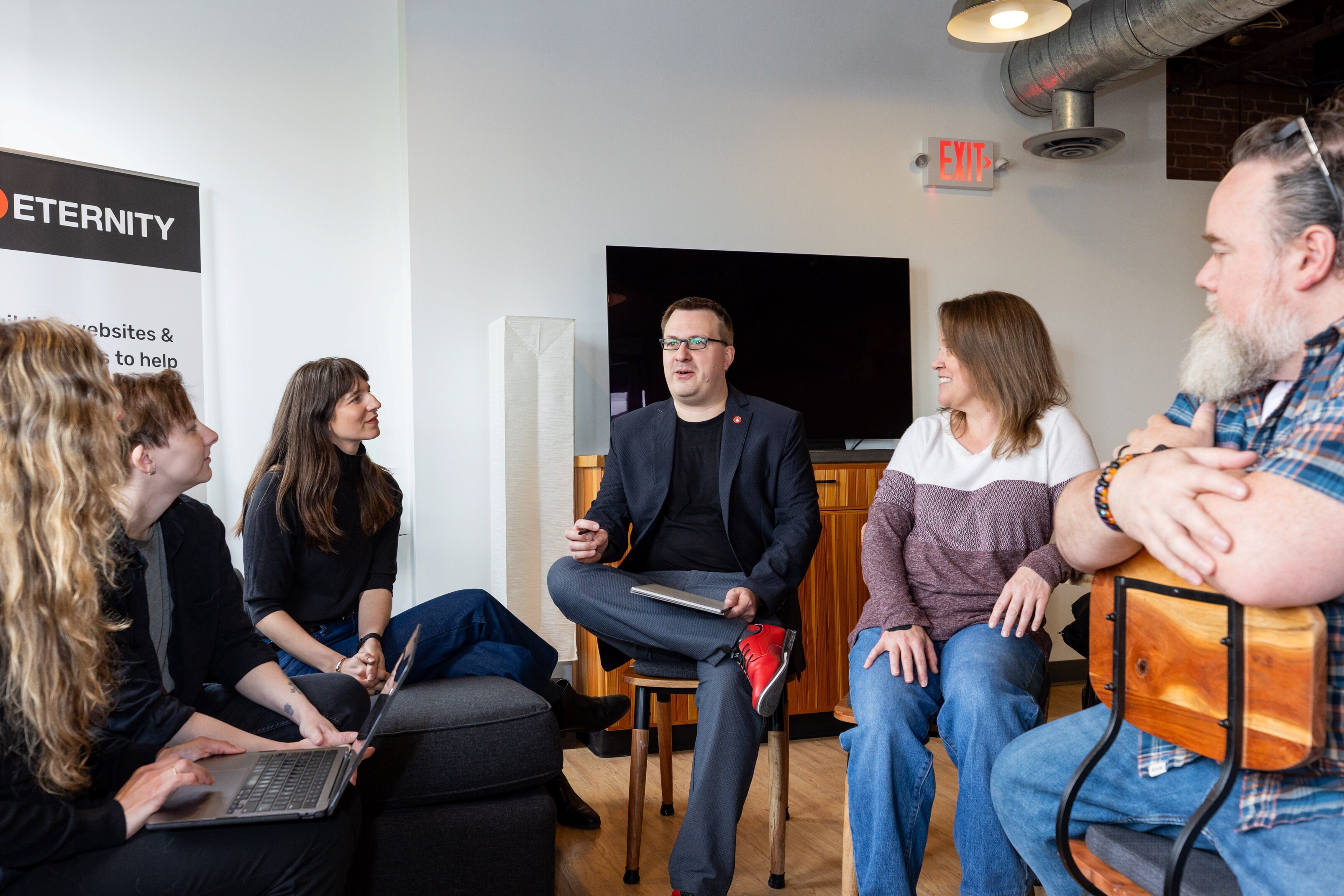 A diverse group of people engaged in discussion around a table in a modern office setting.