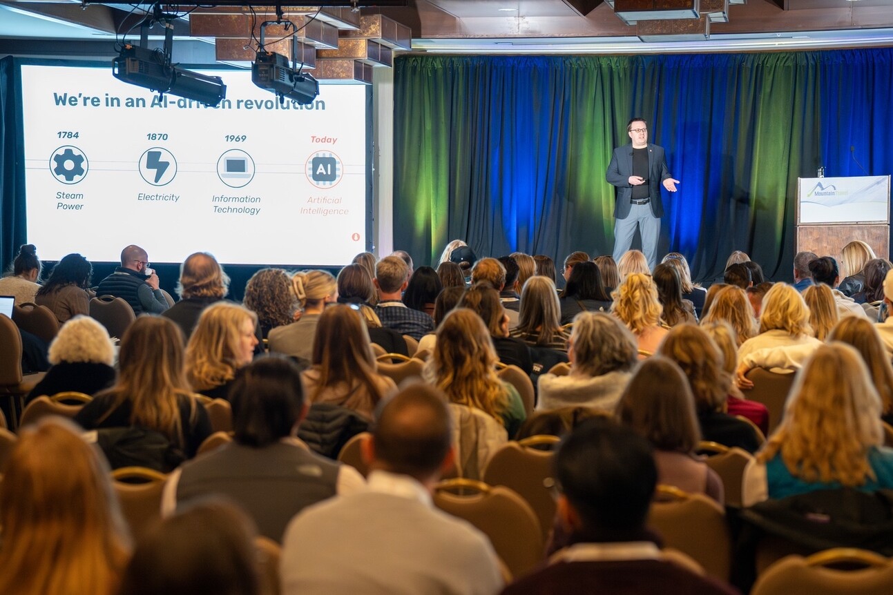 A speaker presenting on AI's impact to an audience at a conference.