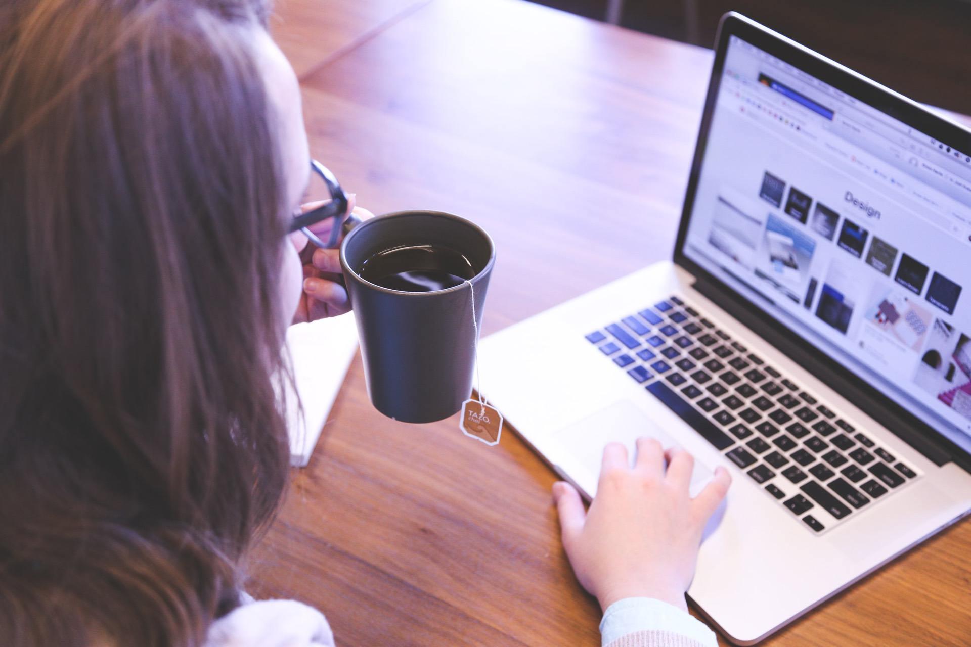 woman searching on laptop drinking tea
