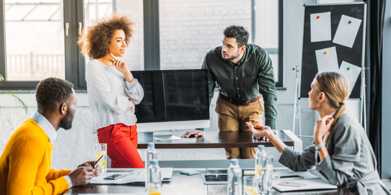 Young multicultural businesspeople in a meeting discussing competitor keywords.