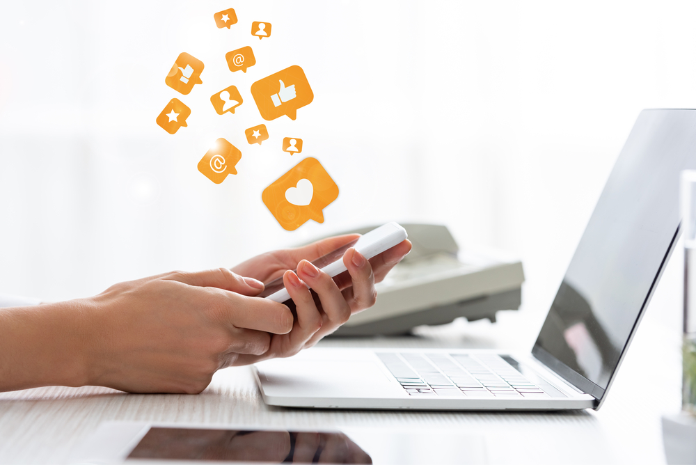 Person Holding Phone With Likes and Shares Social Graphics