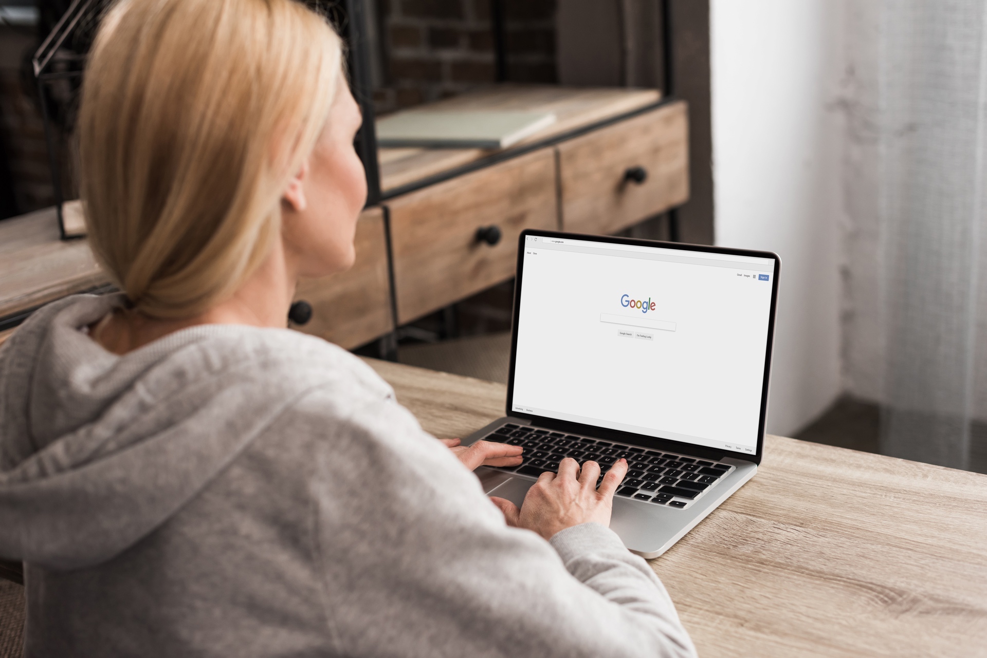 google knows everything about you blonde woman using a laptop at a table with the google search page on it